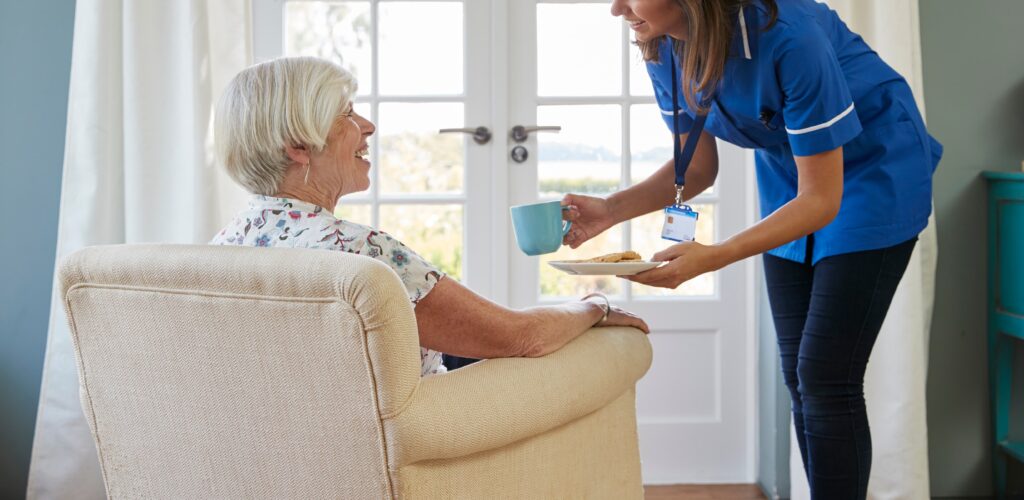 Nurse serving tea and biscuits to senior woman