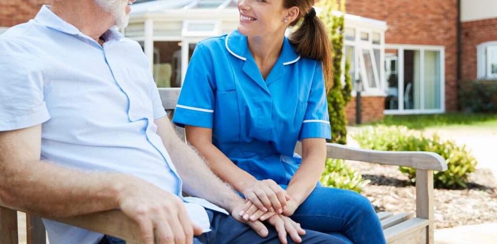 senior man sitting on bench and talking with nurse